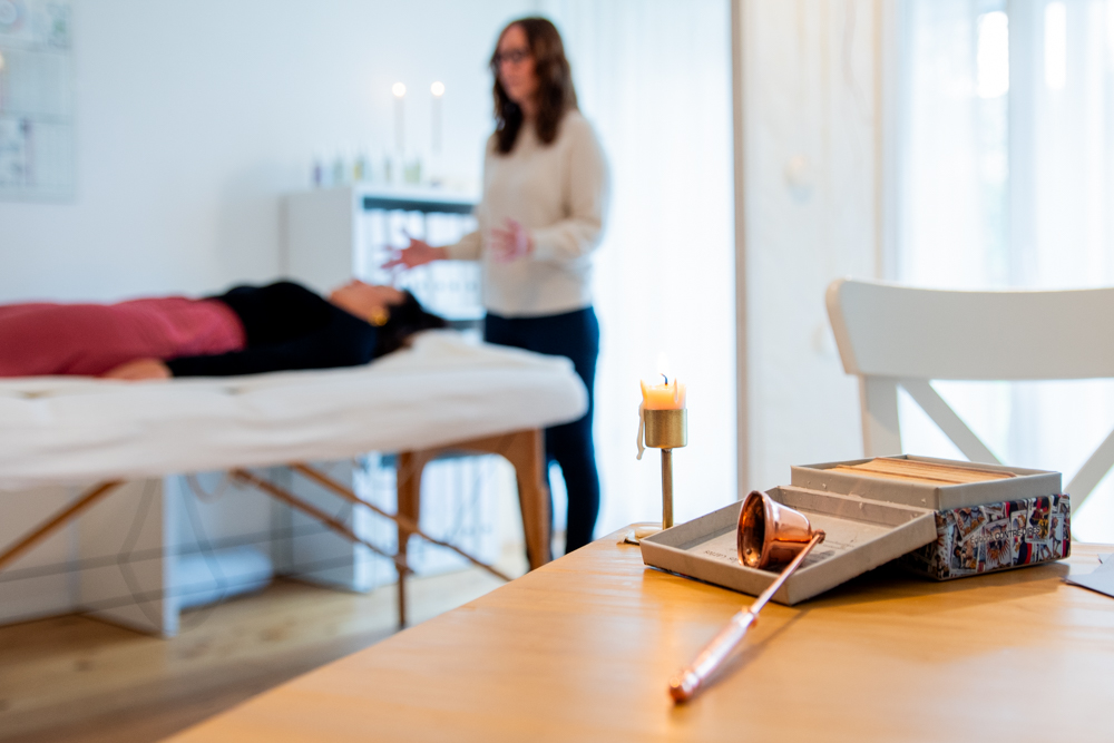 Calming spa setup featuring a jade roller, gua sha stone, and candle for relaxation and skincare.